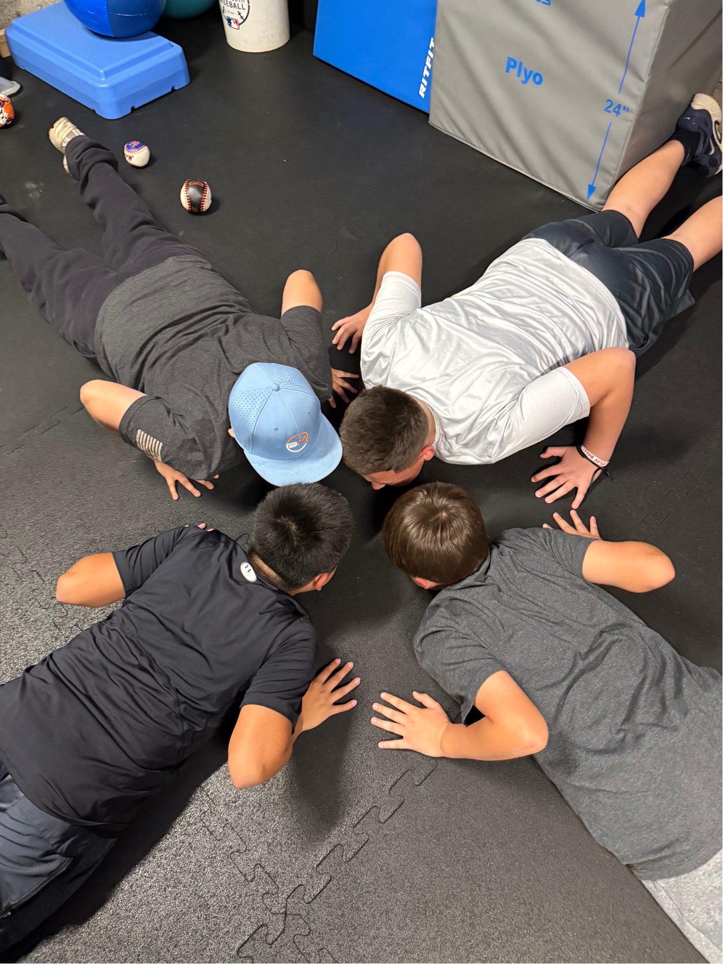 Youth athletes doing group push-up circle in gym
