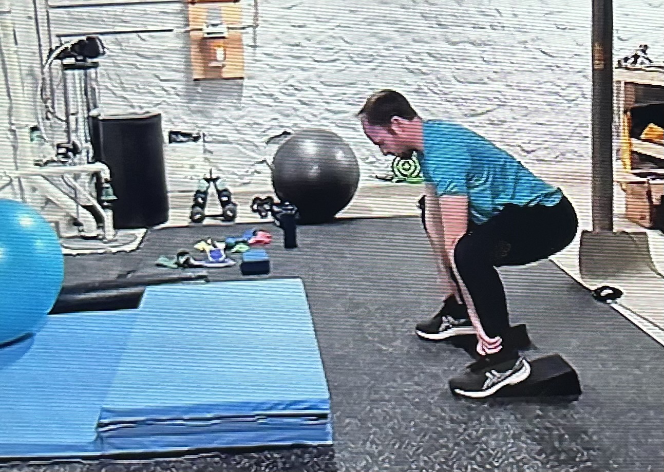 Online client doing banded deadlift in home gym