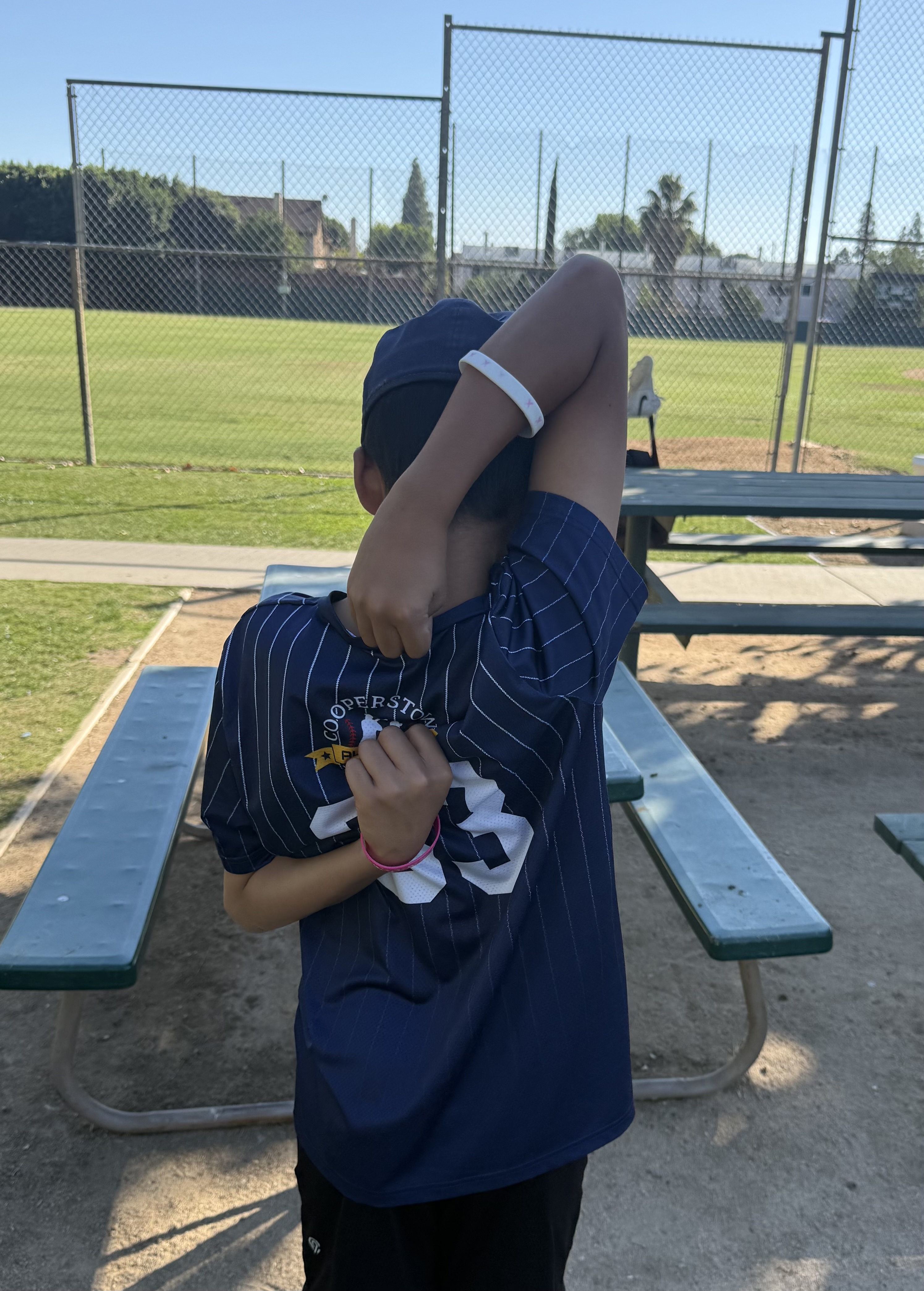 Youth baseball player stretching arms behind back at the field